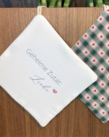 Topflappen mit Aufdruck „Geheime Zutat Liebe“ und grün-rotem Herzmuster